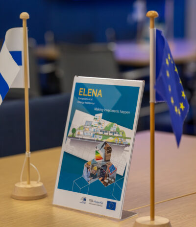Pöydällä pienet Suomen ja EU:n liput, joiden välissä ELENA-pöytäkyltti.